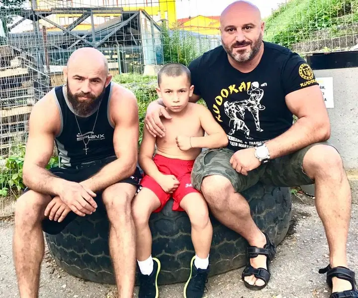 Antrenori Kudokai cu un copil, pe o anvelopă de antrenament