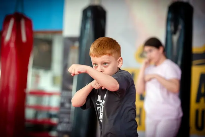 Băiat roșcat în gardă lângă sacul de box